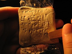 Uno studente si esercita ad incidere sulla gomma pane i segni cuneiformi della didascalia del tributo di Yehu (Obelisco Nero da Nimrud)